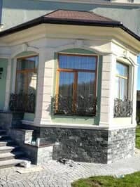 Дом с коваными решётками на окнах цоколя