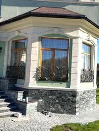 Дом с коваными решётками на окнах цоколя